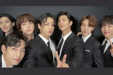 7 integrantes da banda BTS posando juntos para foto vestidos com terno.