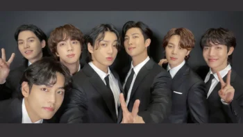 7 integrantes da banda BTS posando juntos para foto vestidos com terno.
