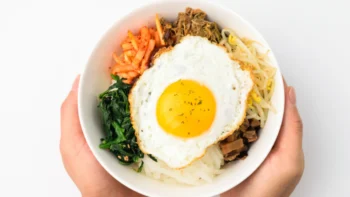 Prato montado de bibimbap com arroz, vegetais e ovo.